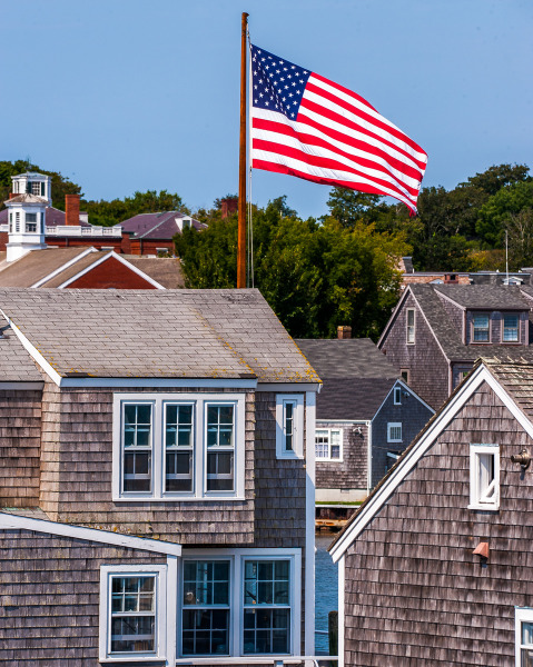 American flag waving above historic Nantucket shingle cottages on a clear day