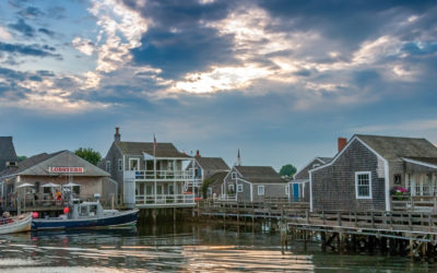 Historic Nantucket wharf with shingle buildings, docked boats, and calm harbor water at sunset